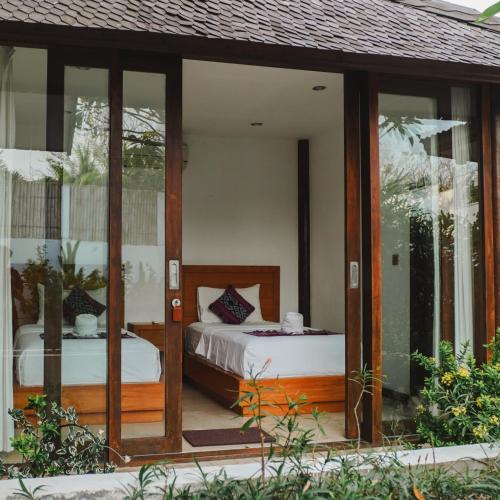 a room with two beds and glass doors at Ningaloo Villa in Gili Trawangan