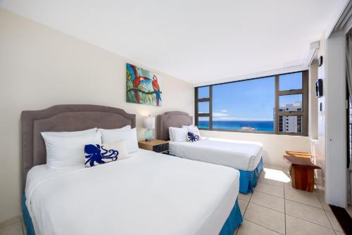 two beds in a room with a large window at 34FL Deluxe Living in Waikiki - Ocean View Condo with Parking in Honolulu