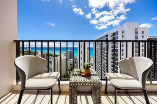 a balcony with chairs and a table and a view of the ocean at 34FL Deluxe Living in Waikiki - Ocean View Condo with Parking in Honolulu