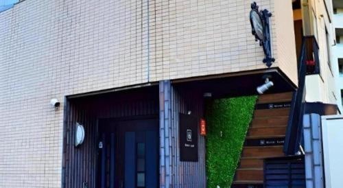a building with a door with green moss on it at HOSTEL LUND I -Oimachi- in Tokyo