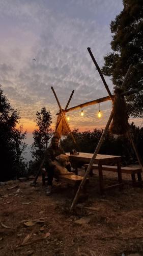 un uomo seduto su un tavolo da picnic di fronte al tramonto di Zelten Bir Luxury Forest Jungle Camps a Bīr