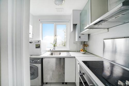 a white kitchen with a sink and a dishwasher at Charming Designer Cosy Loft Apartment in London