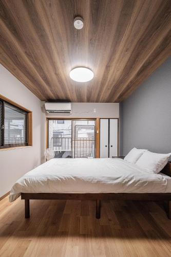 a bedroom with a large bed with a wooden ceiling at 勝清居 大阪獨棟車庫民宿 千日前線新深江站2分一線直達 難波日本橋 全新裝修3LDk in Osaka