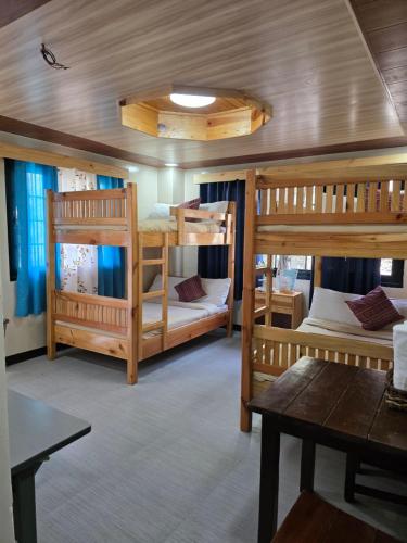a room with three bunk beds and a table at Quarrybay Hometel Sagada in Sagada