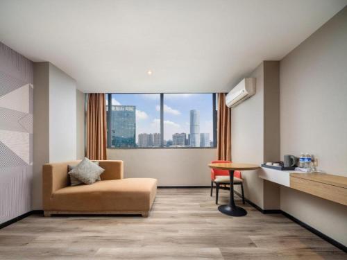 a room with a chair and a table and a window at Borrman Hotel Zhongshan Lihe Plaza in Zhongshan