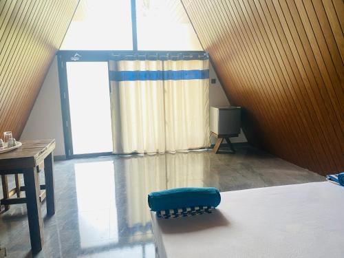 a room with a large window and a blue chair at Wonder of Udawalawe Cottage in Udawalawe
