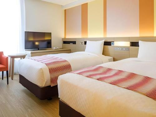 a hotel room with two beds and a television at Hotel Dream Gate Maihama in Chiba