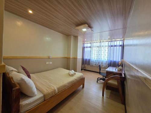 a bedroom with a bed and a desk and a window at Quarrybay Hometel Sagada in Sagada