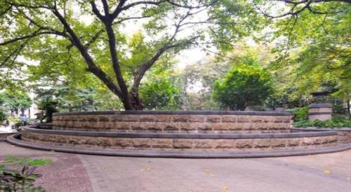 a stone bench in a park with a tree at New Pearl River Hotel in Guangzhou