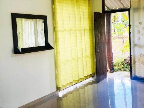 a room with a door and a window with yellow curtains at Wonder of Udawalawe Cottage in Udawalawe