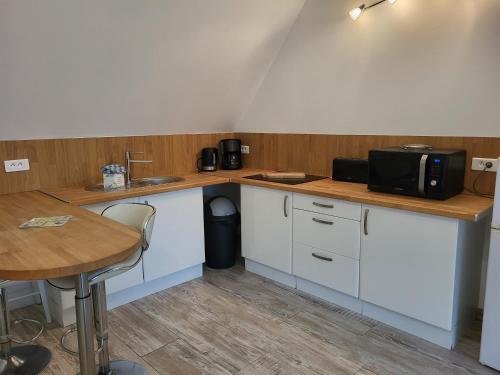 a kitchen with white cabinets and a table and a microwave at Aparthotel Des 2 Caps in Ambleteuse