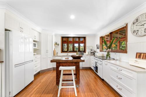 a kitchen with white cabinets and a wooden island at Serene Farm Stay, Modern 3BD, Central Tilba near Mystery Bay! Pets OK in Central Tilba