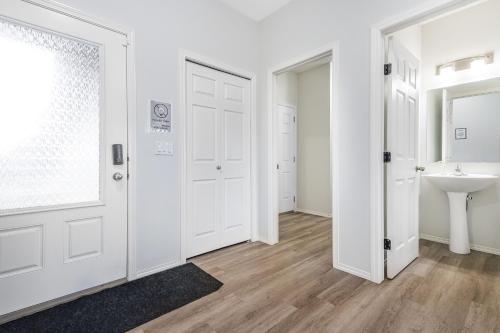 La salle de bains est pourvue d'un lavabo et d'une porte blanche. dans l'établissement EasyStay - Close to Edmonton Airport, Shared Washroom, à Edmonton