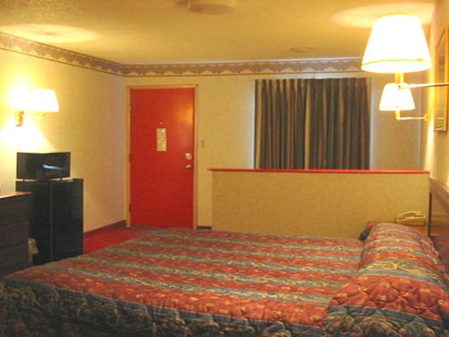 um quarto de hotel com uma cama e uma porta vermelha em Red Carpet Inn Williamstown em Williamstown