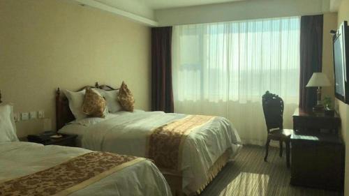 a hotel room with two beds and a window at Yanji Yanbian International Hotel in Yanji