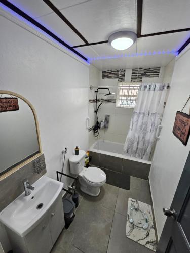 a bathroom with a sink and a toilet and a tub at Sunrise Haven Holiday Apartments Barbados in Christ Church