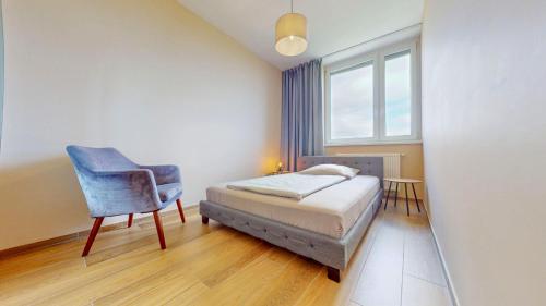 Un dormitorio con una cama y una silla y una ventana. en Koloseo apartman, en Bratislava