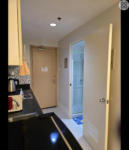 a kitchen with a sink and a door to a bathroom at FinkSea @ Sea Residences in Manila