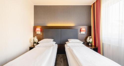 a row of four beds in a hotel room at Best Western Plus Plaza Hotel Graz in Graz