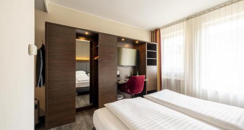 a hotel room with a bed and a red chair at Best Western Plus Plaza Hotel Graz in Graz