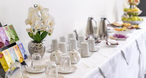 a long white table with white flowers in a vase at Best Western Plus Plaza Hotel Graz in Graz