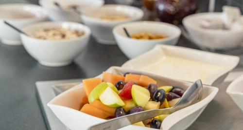 a bowl of fruit on a table with bowls of food at Best Western Plus Plaza Hotel Graz in Graz