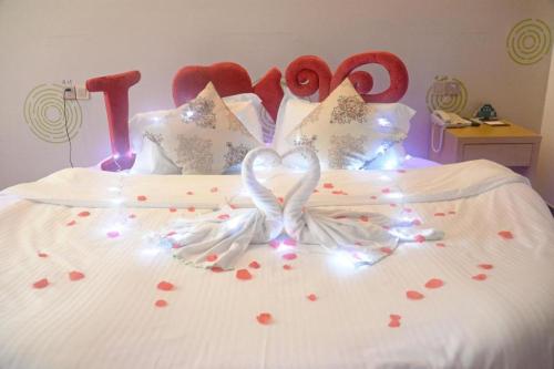 a bed with two white swans with hearts on it at GreenTree Inn Nantong University Industrial Expo City Express Hotel in Nantong