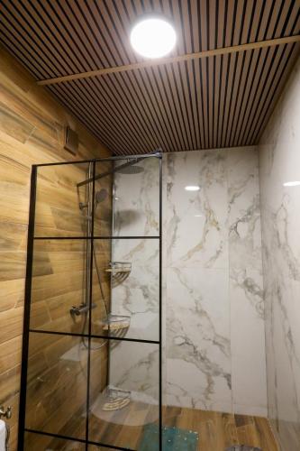 a glass shower in a room with a marble wall at Петров 3 in Bŭnzareto