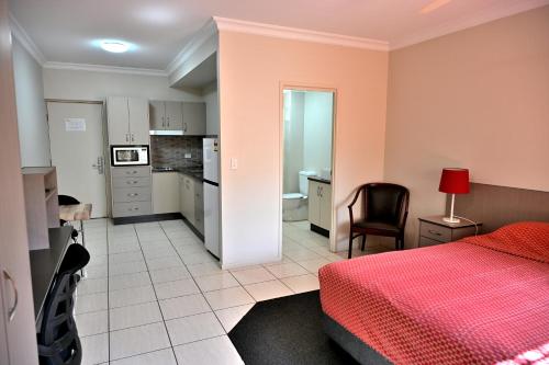 エメラルドにあるWestern Gateway Motel and Apartmentsのベッドルーム1室(赤いベッド1台付)、キッチンが備わります。