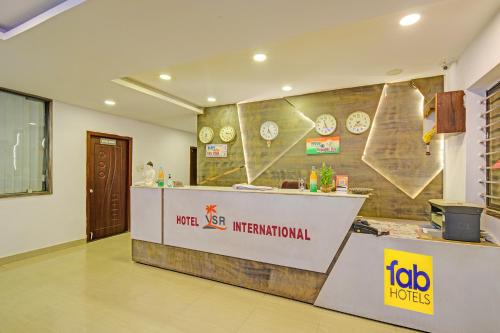 a restaurant with a counter and clocks on the wall at FabHotel VSR International in Shamshabad
