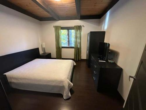 a bedroom with a white bed and a television at Nature & confort - Refuge L'Equilibre in Scott