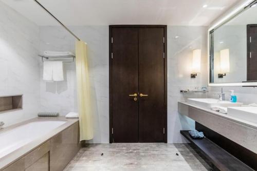 a bathroom with a tub and two sinks and a wooden door at International Conference Hotel Nanjing in Nanjing