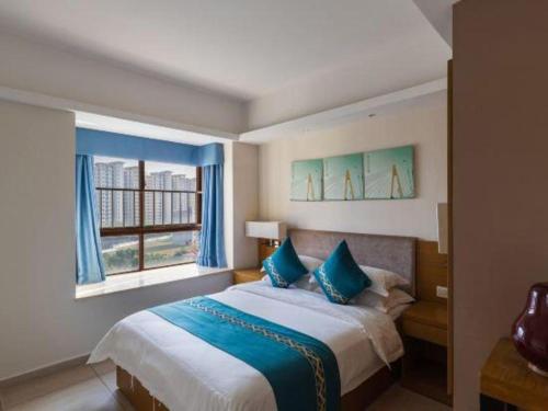 a bedroom with a large bed and a window at Da Peng Zhongzhou Hotel in Haikou