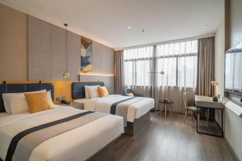 a hotel room with two beds and a desk at Home Inn Selected Xiamen University Zhongshan Road in Xiamen