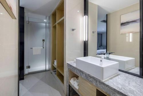 a white bathroom with a sink and a shower at Echarm Hotel Beihai Railway Station in Beihai