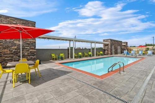 a swimming pool with a table and chairs and an umbrella at Home2 Suites By Hilton Marion in Marion