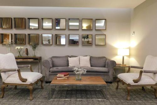 a living room with a couch and two chairs and a table at Hotel Palacio Azteca Tijuana, Trademark by Wyndham in Tijuana