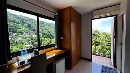 a bathroom with a sink and two large windows at Coco Mountain View Guest House Hotel in Kata Beach