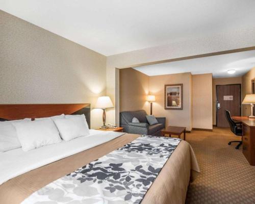 a hotel room with a large bed and a chair at Rodeway Inn & Suites Salina South in Salina