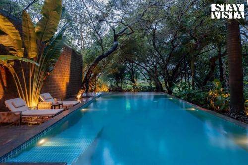 a swimming pool with trees in the background at StayVista at Moira by the River with Bonfire, BBQ in Moira