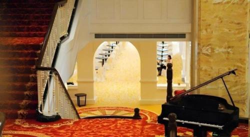 a room with a piano and stairs with wine racks at Adimulia Hotel Medan in Medan