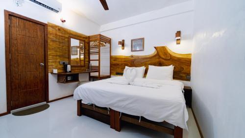 a bedroom with a large bed with a wooden headboard at All Inclusive Stays by Excited Tours - Dhiffushi in Dhiffushi