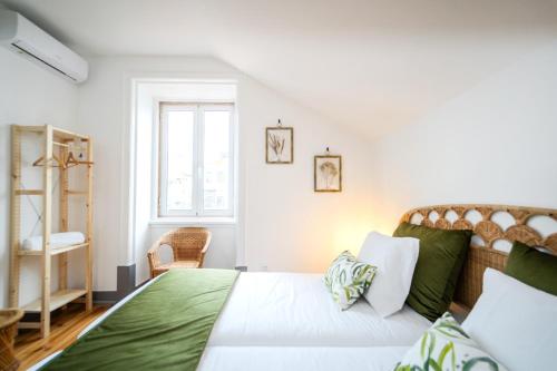 a bedroom with a bed with green sheets and a window at Bairro Novo - Alojamento Local in Figueira da Foz