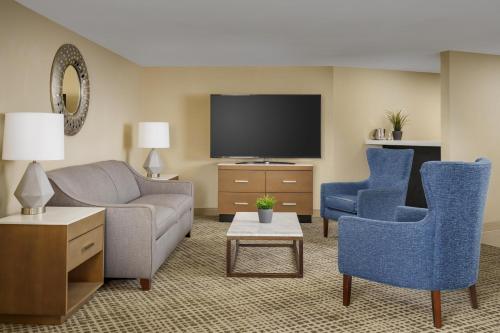 a living room with a couch and chairs and a tv at DoubleTree by Hilton Orlando Airport Hotel in Orlando