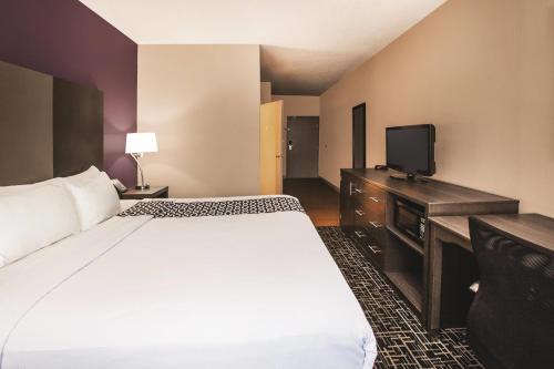 a hotel room with a bed and a flat screen tv at La Quinta Inn by Wyndham Indianapolis North in Indianapolis
