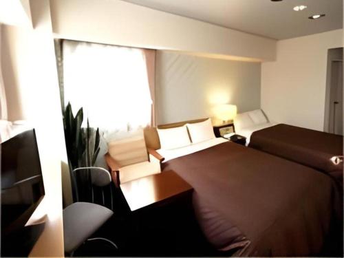 a hotel room with a bed and a window at Hotel Livemax BUDGET Chitose in Sapporo