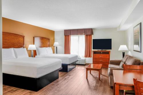 a hotel room with two beds and a television at Days Inn & Suites by Wyndham Sherwood Park Edmonton in Sherwood Park
