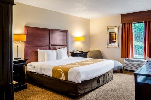 a hotel room with a large bed and a chair at Quality Inn Moss Point - Pascagoula in Moss Point