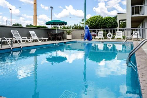 a large swimming pool with chairs and an umbrella at Quality Inn Moss Point - Pascagoula in Moss Point
