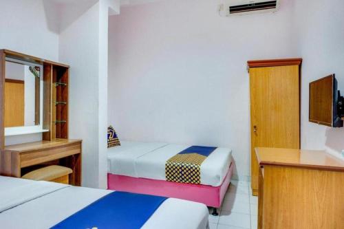 a bedroom with two beds and a desk and a mirror at Wisma Jampea in Makassar